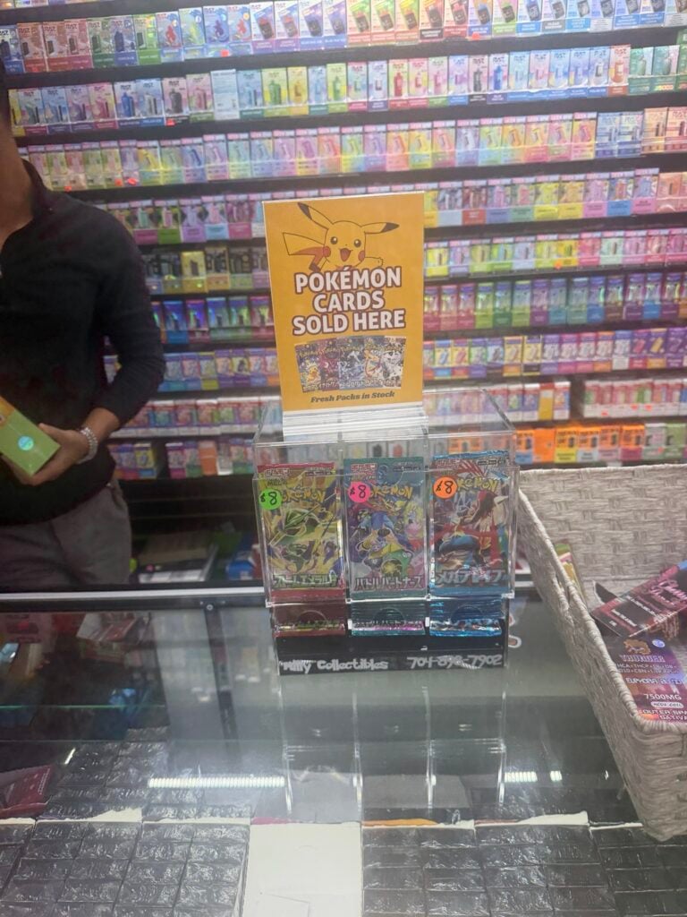 Actual Milly Collectibles Pokémon card display on a store counter beneath a yellow sign
