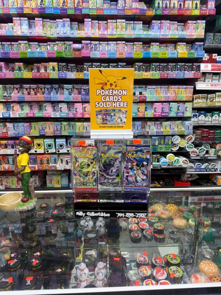 Actual Milly Collectibles Pokémon card display with yellow sign on a glass retail counter